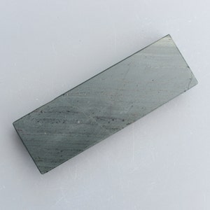 May include: A dark green rectangular sharpening stone with a rough surface.