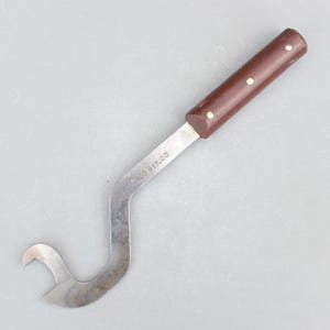 May include: A curved, stainless steel tool with a brown handle. The handle has three small, round, light-coloured accents. The tool has a hooked end and the text "405 817.00" is printed on the metal.