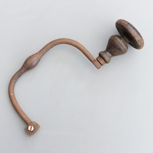 以下が含まれることがあります： 木製のハンドルが付いたさびた金属製のドリル。ドリルは木に穴を開けるために使用されます。