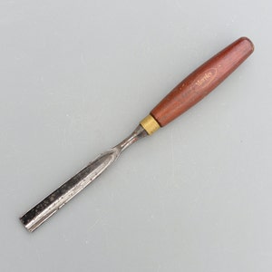 Peut inclure: Un ciseau à bois avec une lame en métal. Le manche est en bois brun et porte l'inscription "Marples".
