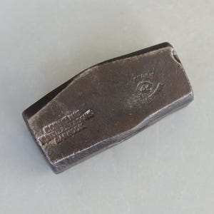 Può includere: Un primo piano di una testa di martello in metallo nero con la scritta "CONVERTIBLE WRENCH & TOOL CO. NEW YORK" impressa sul lato.