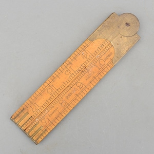 May include: A vintage wooden folding ruler with brass accents. The ruler is marked with black numerals and lines, and the text "RABONE" and "ENGLAND" are visible. The ruler measures up to 10 inches when fully extended.