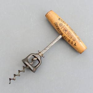 以下が含まれることがあります： 木製のハンドルと金属製のワームが付いたビンテージのコルク抜きで、ハンドルには「MYERS & COMPANY, DIST. FULTON KY. U.S.A.」の文字が印刷されています。