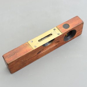 以下が含まれることがあります： 真鍮製のレベルインジケーターと黒い円形の気泡レベルが付いた木製のレベル。レベルには「Starrett」と「Made in U.S.A.」のラベルが付いています。