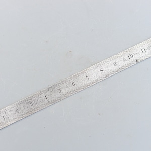May include: A silver metal ruler with black markings, numbered 1 through 12.