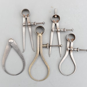 May include: Five silver metal calipers, a tool used for measuring the inside and outside diameters of objects.