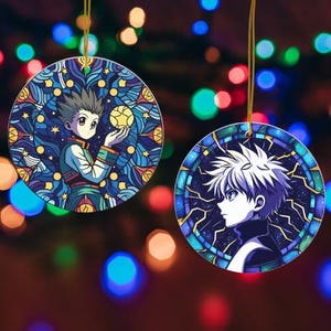 May include: Two round, anime-style ornaments with gold hanging strings. One features a character holding a ball, set against a blue and purple stained-glass design. The other shows a profile of a character with white hair, framed by a blue and purple border.