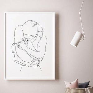May include: A framed black and white line art print depicting two figures embracing. The artwork is minimalist, with a focus on the outlines of the figures. The print is displayed on a light-colored wall, with a white frame.