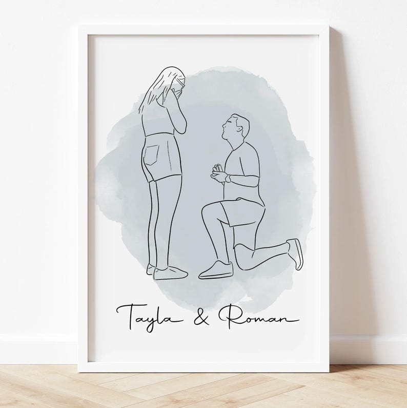 May include: A framed line art print depicts a marriage proposal scene. A man kneels before a woman, both figures outlined in black against a light blue watercolor wash. The names "Tayla & Roman" are written in cursive below the figures.