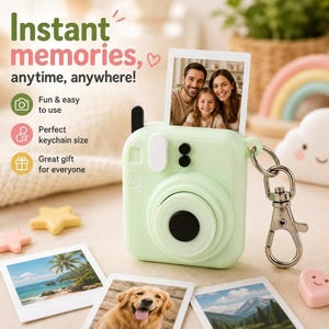 May include: A light green silicone camera-shaped keychain case featuring a central lens cutout, a top antenna, and a metal lobster clasp. The case holds a small square photo of a family, with additional photos of a beach and a dog nearby.