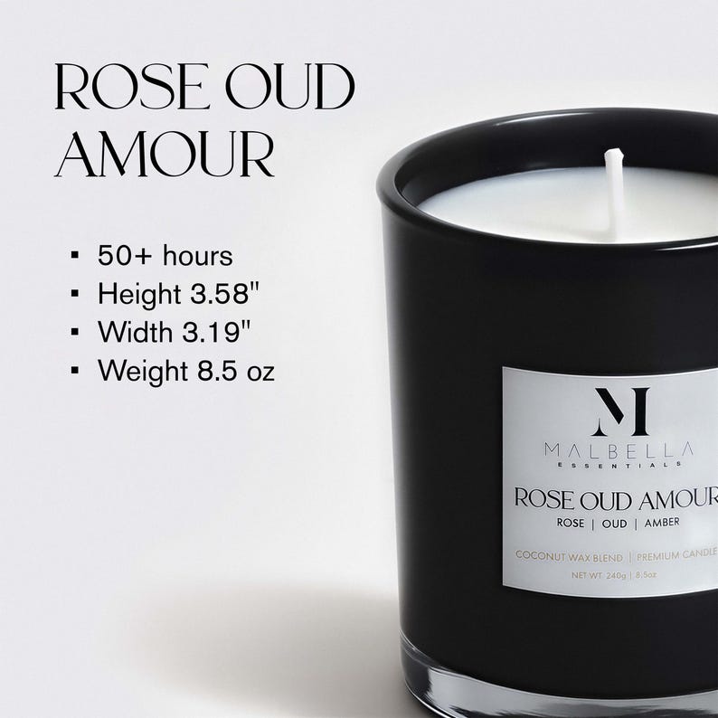 May include: A black glass candle with a white label that reads "ROSE OUD AMOUR." The candle has a white wax interior and a wick. The label also includes the brand name "MALBELLA ESSENTIALS." The candle is 3.58 inches tall and 3.19 inches wide.