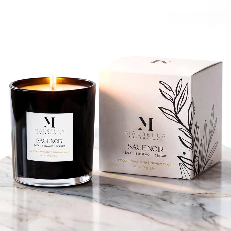 May include: A lit black glass candle with the text "SAGE NOIR" and a white label. The candle is next to a white box with the same text and a botanical illustration. The candle is a coconut wax blend and weighs 140g / 5 oz.