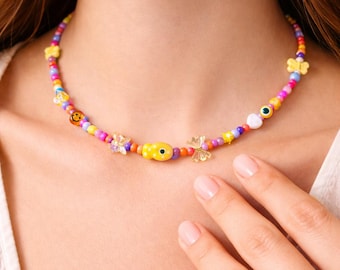 May include: A colorful beaded necklace featuring a variety of beads in shades of yellow, pink, purple, and blue. The necklace includes smiley faces, butterflies, and other decorative elements. The necklace is a fun and playful accessory.