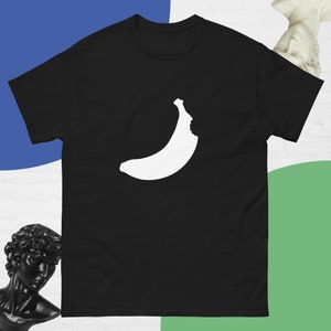 以下が含まれることがあります： 白いバナナのシルエットが顔の中に描かれた黒いTシャツ