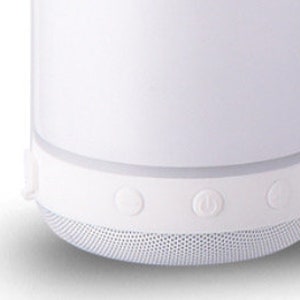 May include: White portable Bluetooth speaker with three buttons on the bottom. The buttons are for power, volume up, and volume down.