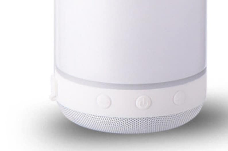 May include: White portable Bluetooth speaker with three buttons on the bottom. The buttons are for power, volume up, and volume down.