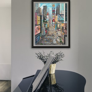 Pu&ograve; includere: Una stampa incorniciata di una vista aerea colorata di Times Square a New York City. L'immagine mostra i cartelloni pubblicitari iconici e il traffico stradale.