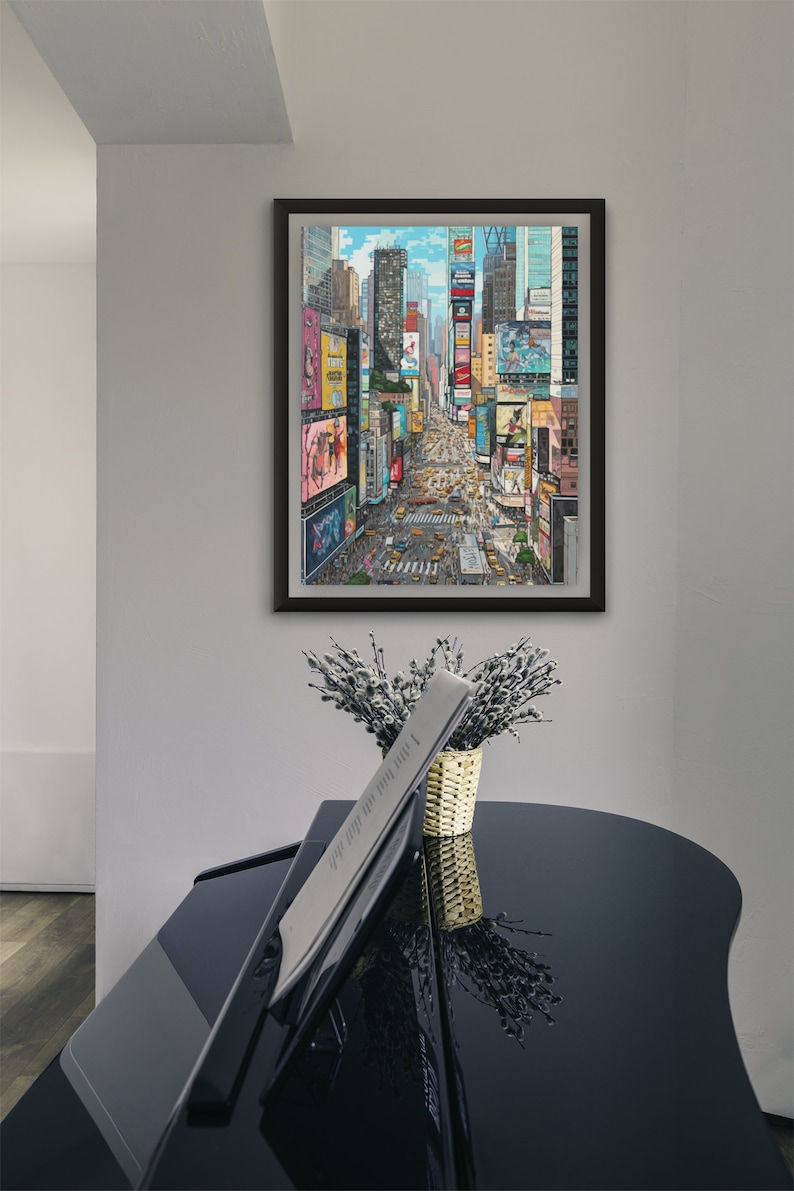 Pu&ograve; includere: Una stampa incorniciata di una vista aerea colorata di Times Square a New York City. L'immagine mostra i cartelloni pubblicitari iconici e il traffico stradale.