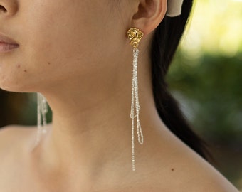 May include: Gold and silver dangle earrings with a textured, abstract design. The earrings are long and feature multiple chains.
