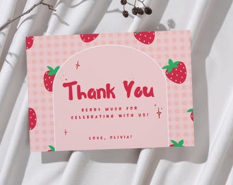 Può includere: Biglietto di ringraziamento rosa con motivo a fragole e la scritta rossa "Thank You". La carta contiene anche le frasi "Berry much for celebrating with us!" e "Love, Olivia!"