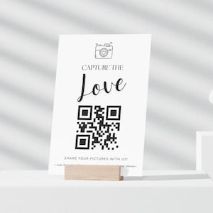May include: White card with a black and white camera icon, the text "Capture the Love" and a black and white QR code. The text "Share your pictures with us!" is at the bottom of the card.