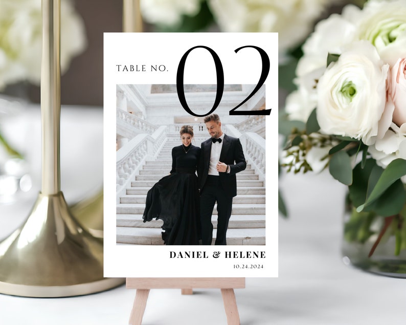 May include: A white table number card with black text and a black and white photo of a couple. The card reads "Table No. 02", "Daniel & Helene", and "10.24.2024".