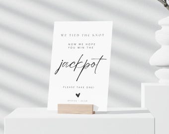 May include: White card with black text that reads "We tied the knot. Now we hope you win the jackpot. Please take one! Olivia & Sean".