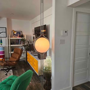 Może przedstawiać: Nowoczesna chromowana lampa podłogowa z dużym, kulistym, matowym szklanym kloszem. Lampa ma elegancki, minimalistyczny design, z okrągłą podstawą i długim, smukłym trzonem. Klosz emituje ciepłą poświatę, idealną do salonu lub sypialni.
