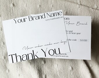 Könnte beinhalten: Eine weiße Dankeskarte mit schwarzem Text, der "Your Brand Name" und "www.YourBrandCom" lautet. Die Karte enthält auch den Text "Your order made our day! Thank You" in schwarzer Kursivschrift. Die Karte liegt auf einer weißen, flauschigen Oberfläche.