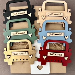May include: Six wooden truck ornaments in different colors, including black, brown, green, blue, gold, and red. Each truck has a "Just married" sign and two small hearts.