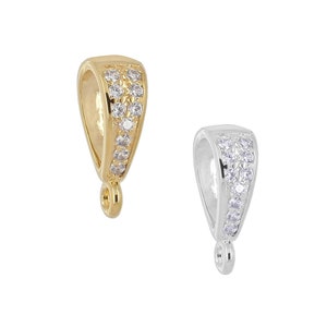 May include: Two pendant bails with a loop at the bottom. The bail on the left is gold with clear cubic zirconia stones. The bail on the right is silver with clear cubic zirconia stones.