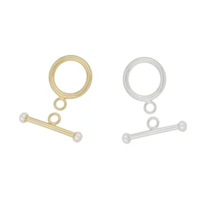 May include: Two gold and silver toggle clasps with pearl accents. The clasps are designed for necklaces or bracelets.