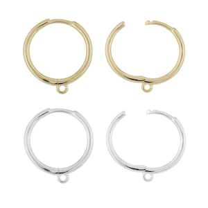 May include: Four hoop earrings, two gold and two silver. Each earring is a circular design with a hinged clasp and a small loop at the bottom for attaching charms or other embellishments. The earrings are displayed against a white background.