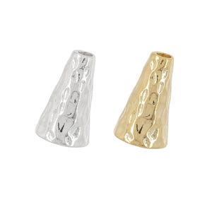 May include: Two hammered metal cone-shaped beads. One is silver, the other is gold. The beads have a textured surface and a flared opening at the top. These beads are suitable for jewelry making.
