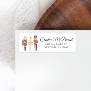 May include: A white rectangular sticker with a watercolor illustration of a Nutcracker, a ballerina, and a mouse king. The text "Chester McDaniel" is written in cursive script. The address "8837 San Pablo St. New York, NY 10002" is printed below the name.