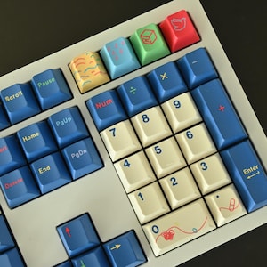 May include: Close-up of a mechanical keyboard with white, blue, and cream-colored keys. The keys are arranged in a standard layout, with a number pad and function keys. Some keys have colorful designs.