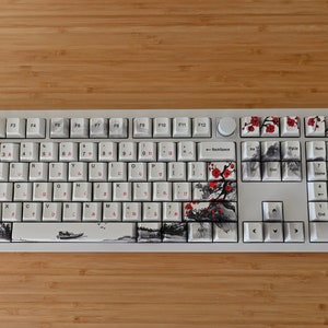 May include: A white mechanical keyboard with a custom keycap set featuring a black and white ink wash design with red blossoms. The design includes a boat, birds, and branches.