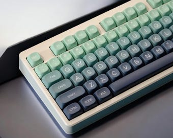 May include: A white keyboard with blue and green keys. The keys have a gradient color effect, starting with a light green and fading to a dark blue. The keyboard has the standard layout with keys labeled ESC, TAB, CAPS, SHIFT, CTRL, CODE, ALT, and the letters of the alphabet.