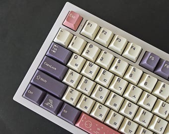 May include: A white keyboard with cream-colored keys and purple and pink accent keys. The keys have both English and Korean lettering. The keyboard has a pink escape key and a pink bottom row.