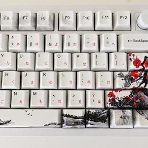 May include: A white mechanical keyboard with Japanese keycaps and a black and white floral design. The keyboard has a white knob on the top right corner.