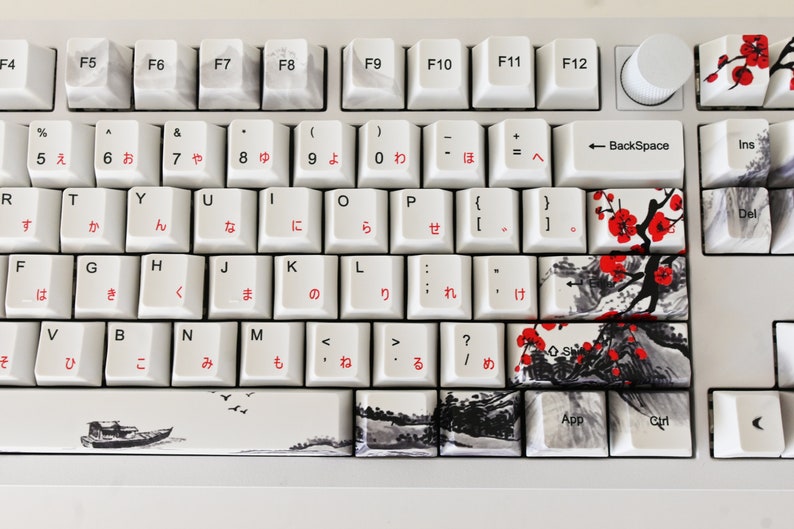 May include: A white mechanical keyboard with Japanese keycaps and a black and white floral design. The keyboard has a white knob on the top right corner.