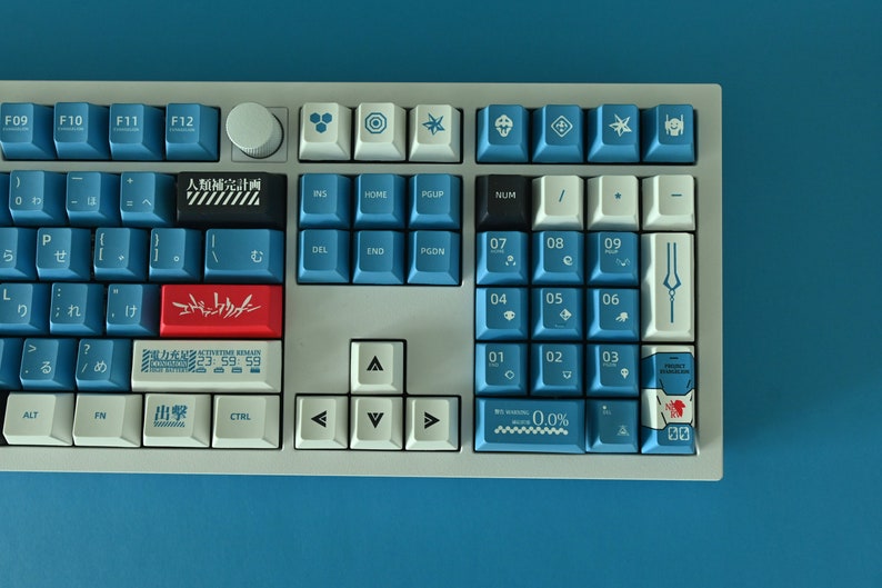 Op de afbeelding: Een wit mechanisch toetsenbord met blauwe en rode toetsen. De toetsen hebben Japanse karakters en symbolen. Het toetsenbord heeft een numeriek toetsenblok en pijltjestoetsen.