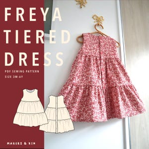 May include: A sleeveless tiered dress with a red and white floral pattern, featuring a button-down back closure. The image includes the text FREYA TIERED DRESS, PDF SEWING PATTERN, SIZE 3M-6Y, and MAKERS & KIN, alongside two line-art illustrations of the dress.