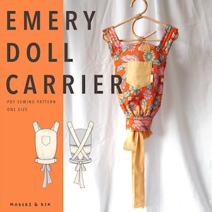 May include: An orange doll carrier with a floral pattern, a solid yellow front pocket, and long yellow ties, hanging on a rattan hanger. The text reads EMERY DOLL CARRIER, PDF SEWING PATTERN, ONE SIZE, and MAKERS & KIN, with two line art diagrams.