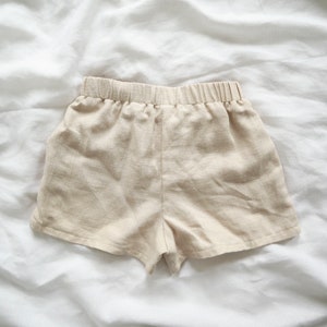 May include: A pair of beige linen shorts with an elastic waistband.