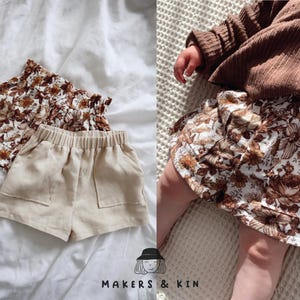 May include: Two pairs of toddler shorts. One pair is beige linen with pockets and the other is white with a brown floral print. The floral print shorts are being worn by a child.
