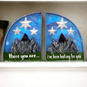May include: A pair of blue and silver bookends shaped like a mountain range with stars in the sky. The left bookend says "there you are..." and the right bookend says "i've been looking for you".
