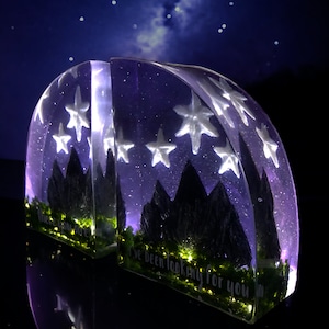 May include: Two clear resin bookends shaped like mountains with a starry night sky and a quote that reads "I've been looking for you".