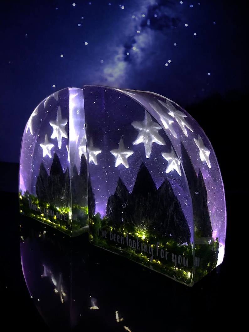 May include: Two clear resin bookends shaped like mountains with a starry night sky and a quote that reads "I've been looking for you".