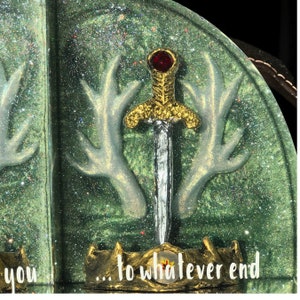 May include: A green and white bookend with a gold sword and red jewel. The bookend features a pair of antlers and the text "...to whatever end".
